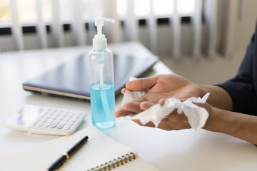 Businessman using hand sanitizer by alcohol gel washing and and wipe tissue paper before start to work with laptop in period,coronavirus or covid19 outbreak. Social distancing and responsibility.