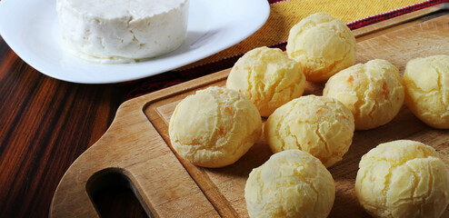 Brazilian cheese bread. Cheese bread portion on the cutting board with white cheese in the background.