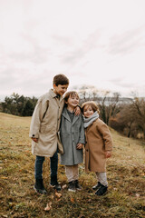 Children hugging, smiling, spending time outdoors in a park on autumn day.