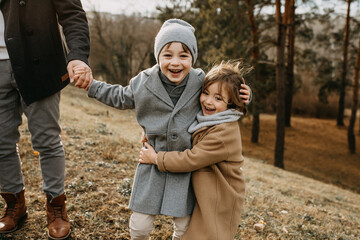 Family walking outdoors on autumn day, spending fun time together. Brothers hugging and laughing.