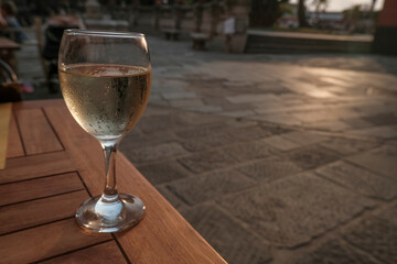 misted glass of white wine on the terrace close-up across the sunset city. Travel, winemaking industry, entertainment