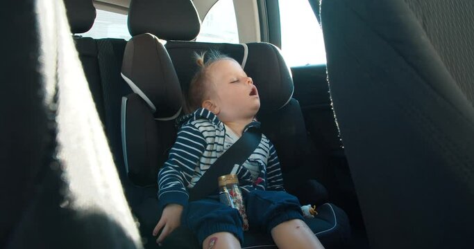 cute baby toddler girl is sleeping on rear setas of vehicle during the travel. Carefree childhood watching dreams on road in the car