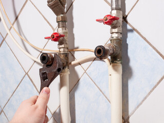 Unscrewing plumbing fittings on water pipeline by old adjustable wrench in male hand. installation of the faucet on the water pipe. Elimination of water leakage. Repair DIY at home.
