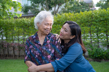 Asian elderly woman with caregiver walking with happy in nature park.