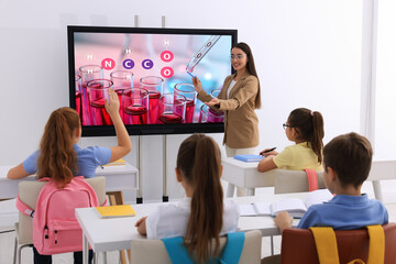 Teacher using interactive board in classroom during lesson - obrazy, fototapety, plakaty