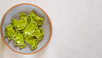 Green dumplings with cottage cheese and spinach on ceramic plate on white background