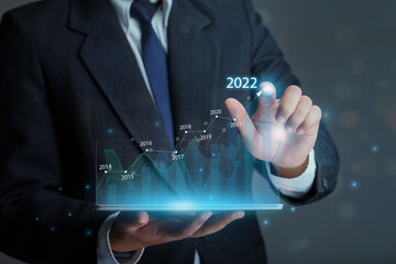  Businessman holding tablet with draws increase arrow graph corporate future growth year 2021 to...