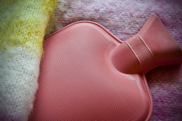 Pink hot water bottle on a wool blanket