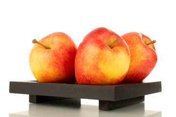 Three organic red apples with a black wooden tray, close-up, isolated on white.