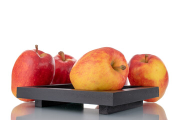 Several organic red apples with a black wooden tray, close-up, isolated on white.