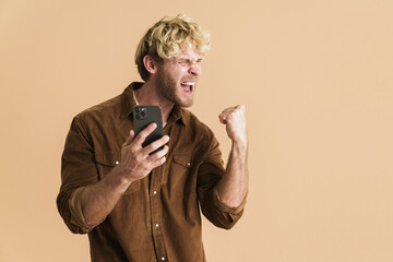 White blonde man making winner gesture while using cellphone