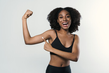 Young black woman laughing and pointing finger at her bicep