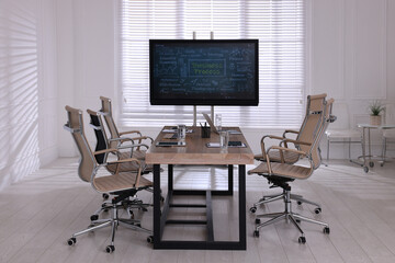 Interactive board near wooden table and chairs in meeting room