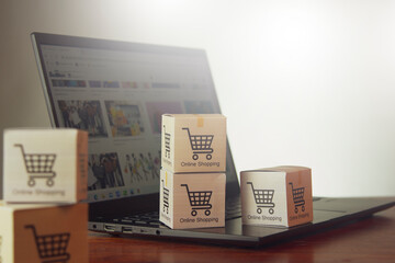 Obraz premium Online shopping/ecommerce and shipping concepts: A cardboard box with a cart or cart logo on a laptop keyboard represents a customer placing an order from a retail store over the Internet.