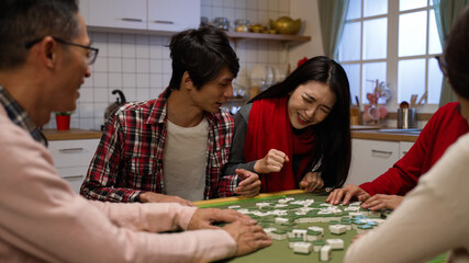 asian brother elbowed his sister out of chair while they are fighting at mahjong table. wagging...