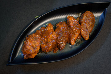 Chicken stuffed pan fried momo, a popular food in India, served on a black plate on a black...