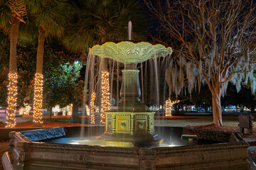 Caterina fountain in a basin in a public park. Long exposure, night, holiday decorations on background trees.