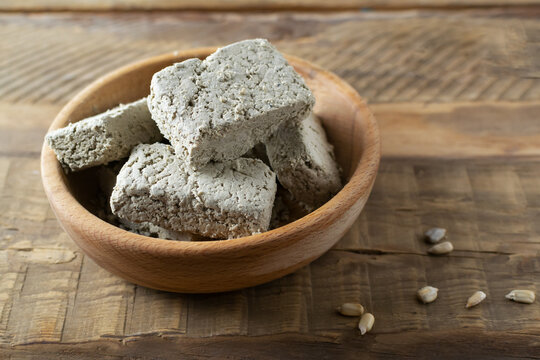 Sunflower halva in a wooden bowl on a wooden table. Rustic style. Traditional sweets. Vegetarian food. Copy space.