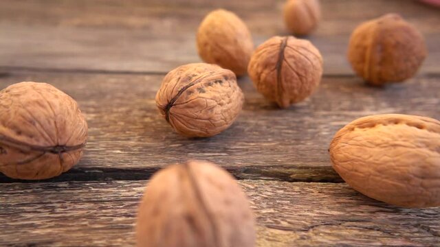 Walnuts are falling on the old wooden vintage board. Slow motion. Juglans regia.