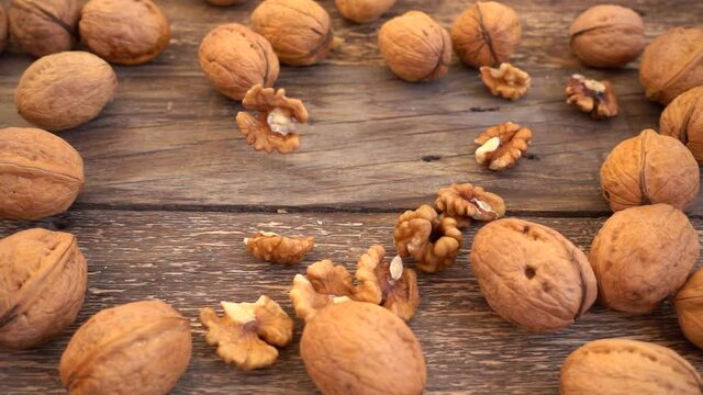 Walnut kernels are falling on the old wooden vintage board. Slow motion. Juglans regia.