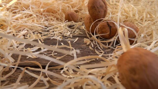 Walnuts fall on straw and old wooden vintage board. Slow motion. Juglans regia.
