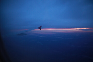 View from the porthole of the airplane window to the sky and the dawn of the sun, airplane wing