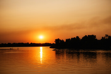 Fototapeta na wymiar orange sunset on the river with silhouettes