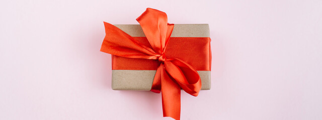 Banner made of Present box with red bow on pink background. Flat lay, top view, copy space.