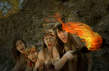Four girls are dressed as Neanderthal warriors. Their 
faces are filled with anger and are seen...