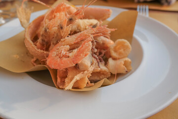 Fried seafood on the white plate close-up in the restaurant. shrimps, octopus, calamari on a plate. Mediterranean cuisine 