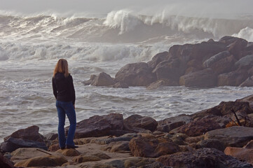 Woman watches storm waves come ashore.