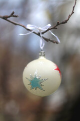Vintage Christmas ornament hanging on a bare tree in a garden. Selective focus.