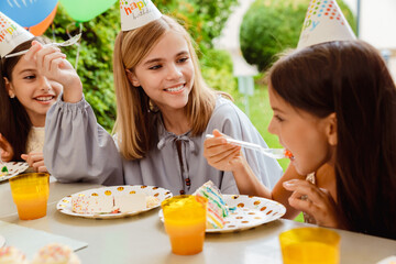 Multiracial girls making fun while eating cake during birthday party