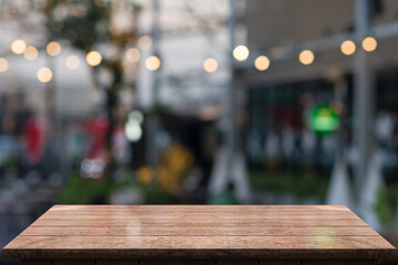 Empty wooden table top with lights bokeh on blur restaurant background.