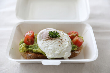 Poached eggs with avocado on toast with delivery package in white background