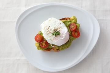 Poached eggs with avocado on toast in white background