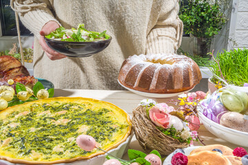 Festive dinner, Easter brunch. Traditional Easter dishes on family home table - baked meat, quiche, spring salad, muffin, colored eggs, hot cross buns