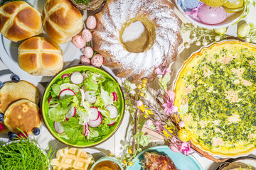 Festive dinner, Easter brunch. Traditional Easter dishes on family home table - baked meat, quiche, spring salad, muffin, colored eggs, hot cross buns