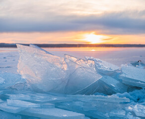 the sun shines through the  transparent  ice at sunset, on the shore of a forest lake covered with snow in cold winters.. © Lana Kray