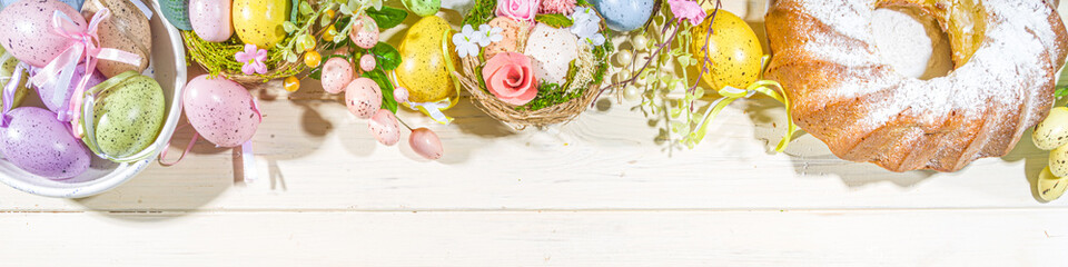 Easter painted colorful pastel eggs in a basket, with feathers on a light wood background. Easter greeting card composition, spring holiday still life background
