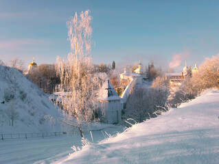 Birch in hoarfrost on the background of Holy Dormition Pskovo Pechersky Male Monastery in the town of Pechora, Pskov Region, Russia, on a winter sunny day