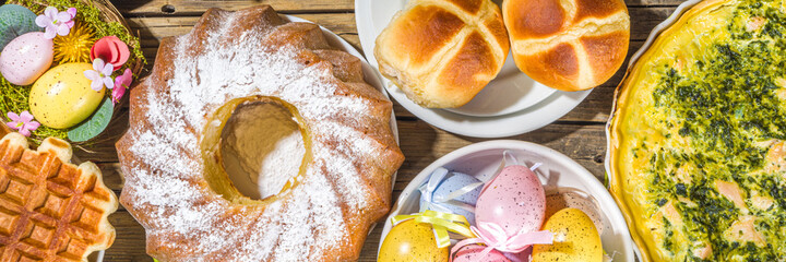Festive dinner, Easter brunch. Traditional Easter dishes on family home table - baked meat, quiche, spring salad, muffin, colored eggs, hot cross buns