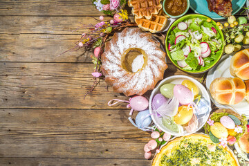 Festive dinner, Easter brunch. Traditional Easter dishes on family home table - baked meat, quiche, spring salad, muffin, colored eggs, hot cross buns