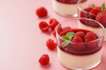 Italian dairy dessert panna cotta with raspberry jam, fresh raspberries and mint on pink surface, copy space