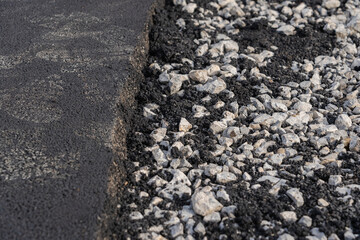 New asphalt pavement on one of the lanes of the road, gravel on the other lane of the road before laying asphalt