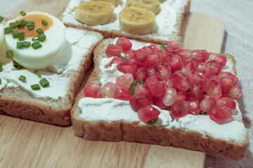 Bread has cream cheese and pomegranate boiled egg banana on red background.