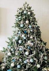 Spruce branches are decorated with white and blue balls, silver snowflakes and details