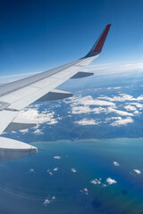 Obraz premium Classic image through aircraft window onto wing. Flight view over sea in cloudy weather