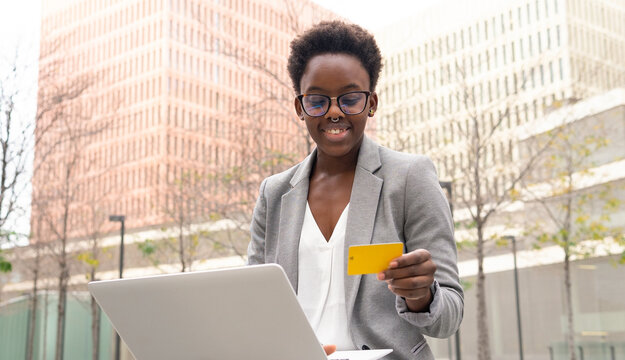 Smiling African American businesswoman paying with credit card using laptop