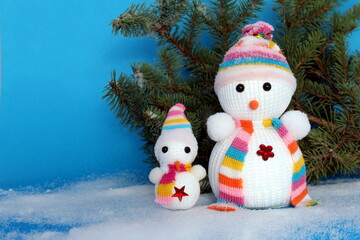 Christmas theme. A snowman in a hat and scarf stands in the snow against a frost background.